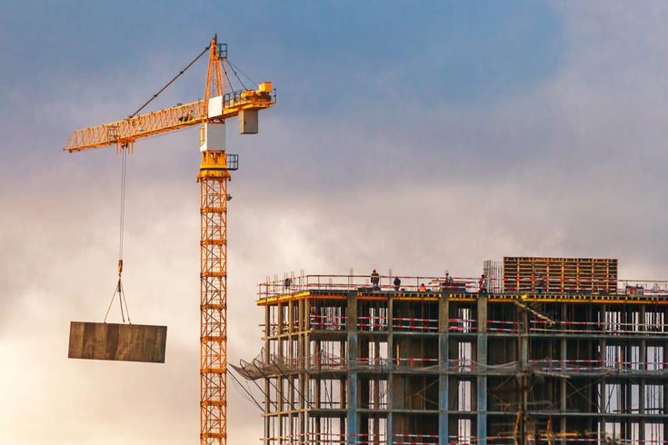 Multi-storey building under construction with a tower crane at dusk